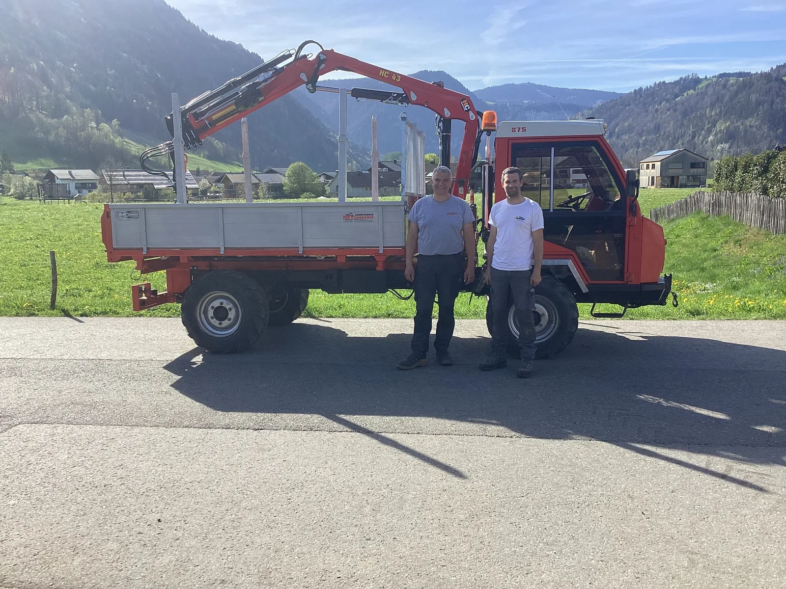 Reform Muli 875 mit Dreiseitenkipper und HC-43-Kran, zwei Mitarbeiter daneben